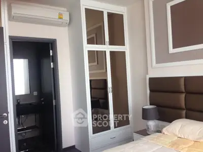 Modern bedroom with stylish decor and ensuite bathroom, featuring sleek wardrobe and air conditioning.