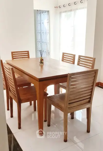 Elegant dining area with wooden table and chairs, bright natural light, perfect for family gatherings.