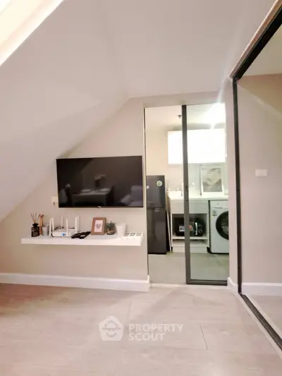 Modern living space with sleek TV setup and compact kitchen area