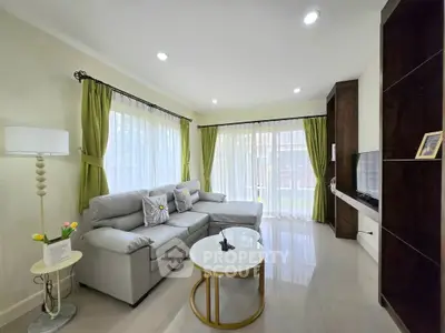 Spacious living room with modern decor, large windows, and elegant furnishings in a cozy home setting.