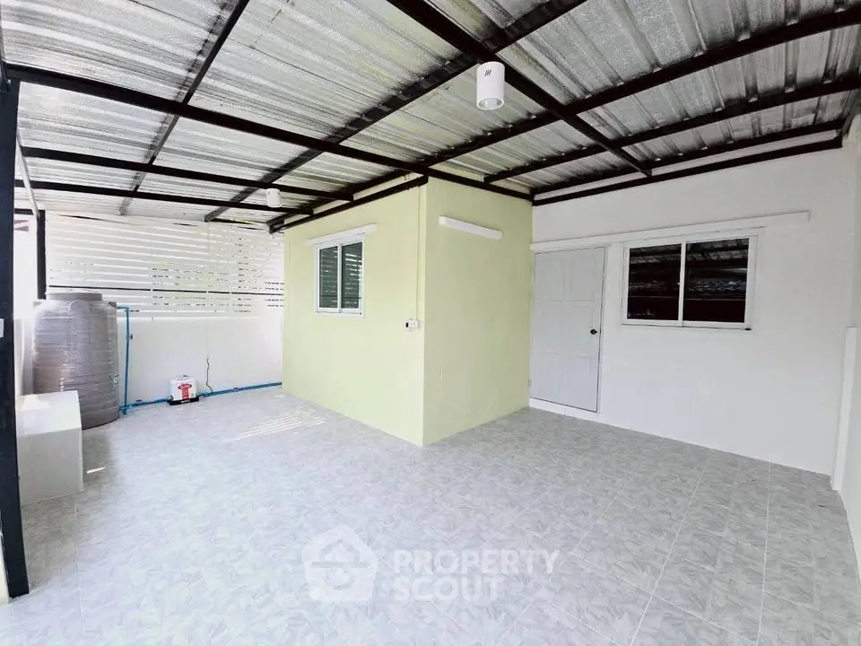 Spacious covered outdoor area with tiled flooring and utility connections.