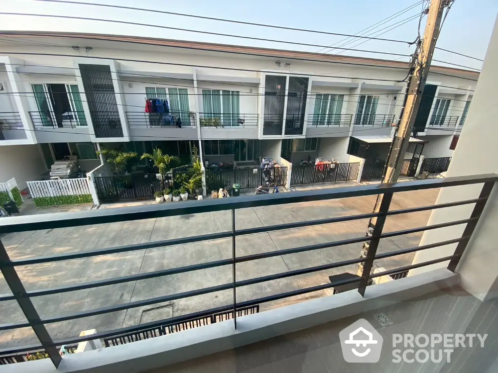 Spacious balcony with a serene view of a modern townhouse complex, showcasing a peaceful suburban lifestyle with ample outdoor space.