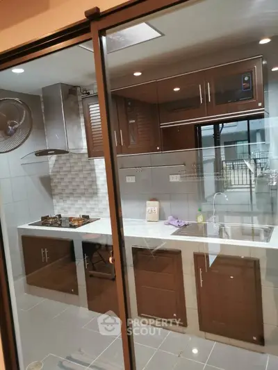 Modern kitchen with sleek cabinets and gas stove, featuring a glass partition for a contemporary touch.