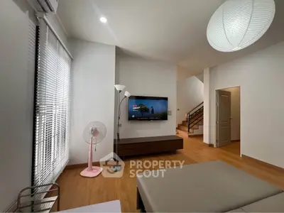 Modern living room with stylish decor and wooden flooring, featuring a wall-mounted TV and contemporary lighting.
