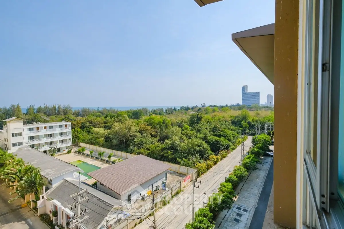 Stunning coastal view from high-rise building with lush greenery and distant ocean.