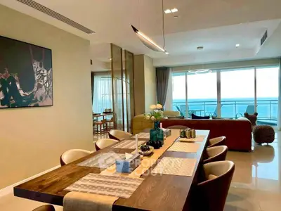 Luxurious open-plan living and dining area with ocean view, modern decor, and elegant lighting.
