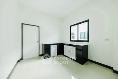 Modern minimalist kitchen with sleek black cabinets and large window