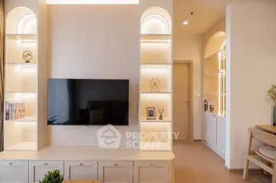 Modern living room with built-in shelves and flat-screen TV, featuring elegant lighting and decor.
