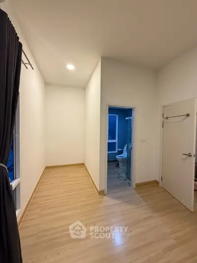 Spacious room with wooden flooring and attached bathroom in modern apartment