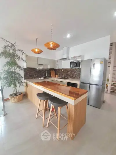 Modern kitchen with island, stylish lighting, and stainless steel appliances