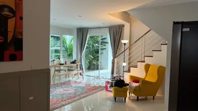 Stylish living room with modern decor and staircase, featuring a cozy reading nook and garden view.