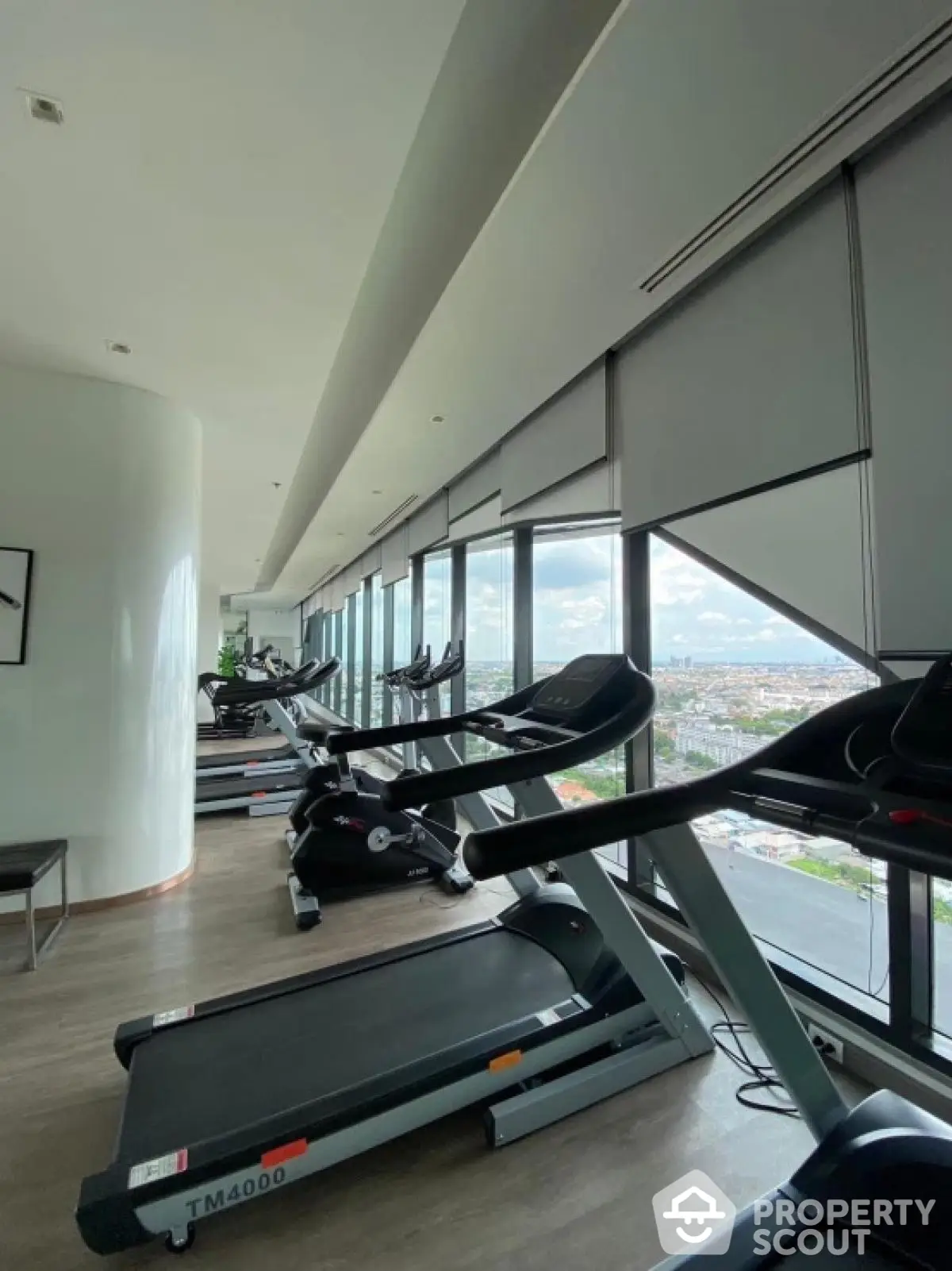 Luxurious high-rise gym with panoramic city views and modern fitness equipment.