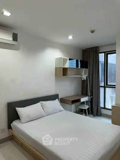 Modern bedroom with minimalist design, featuring a comfortable bed, study desk, and large window for natural light.