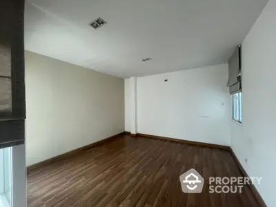 Spacious empty living room with polished hardwood flooring and ample natural light, perfect for custom interior design.