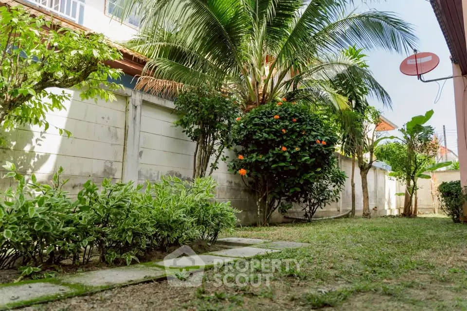 Charming garden with lush greenery and tropical plants in a serene residential setting.