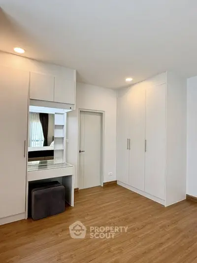 Spacious bedroom with built-in wardrobe and elegant wooden flooring