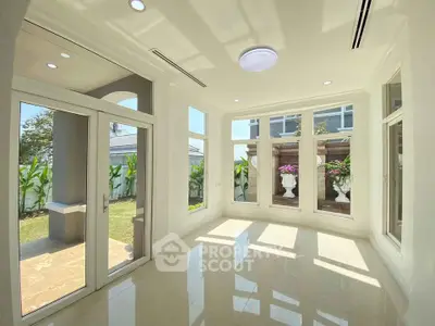 Bright sunlit room with large windows and garden view, perfect for a serene living space.