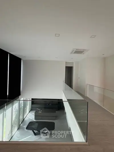 Modern duplex interior with sleek design and glass railing overlooking living area.