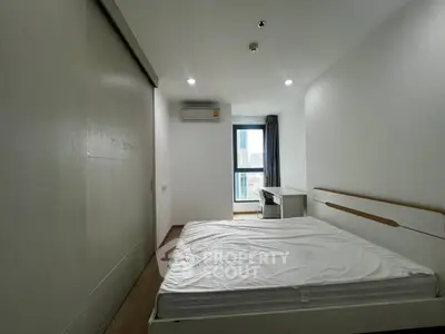 Modern minimalist bedroom with large window and built-in closet in urban apartment.