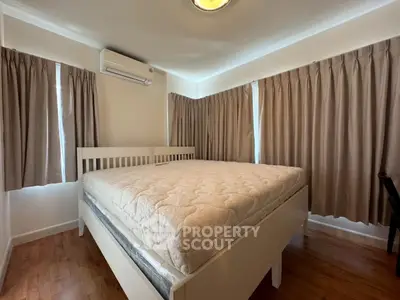 Cozy bedroom with large bed and natural light from curtained windows, perfect for relaxation.