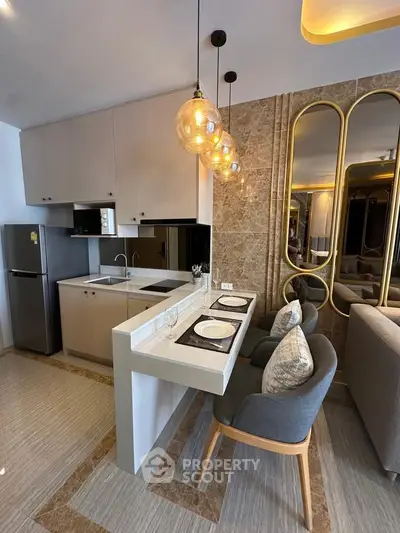 Modern kitchen with stylish lighting and open layout, featuring a breakfast bar and contemporary decor.