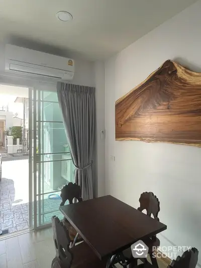 Charming dining area with wooden table and wall art, adjacent to a sunlit patio.