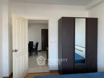 Spacious bedroom with wardrobe and open door leading to dining area