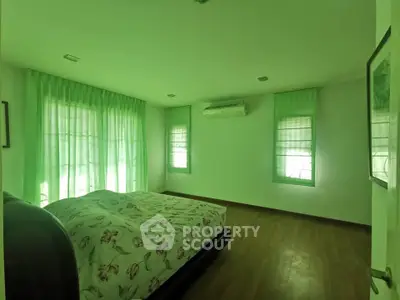 Spacious bedroom with large windows and air conditioning, featuring elegant floral bedding and wooden flooring.