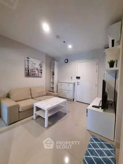 Modern living room with beige sofa, white coffee table, and wall-mounted TV in a cozy apartment.