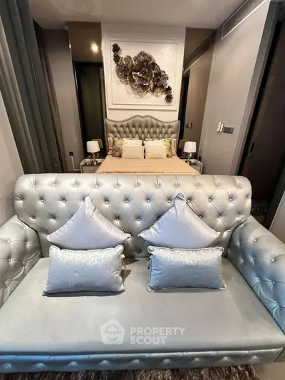 Luxurious bedroom with elegant silver tufted sofa and plush bedding