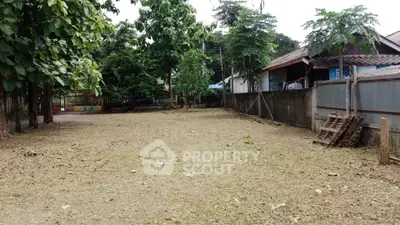 Spacious residential land plot with lush greenery and neighboring houses, ideal for building a dream home.