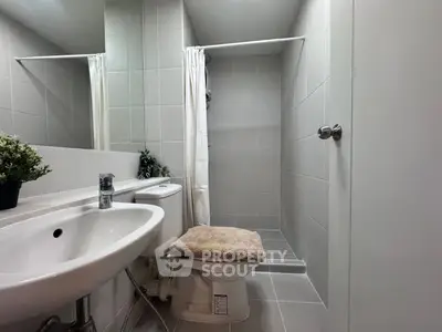Modern bathroom with sleek fixtures and minimalist design, featuring a walk-in shower and contemporary sink.