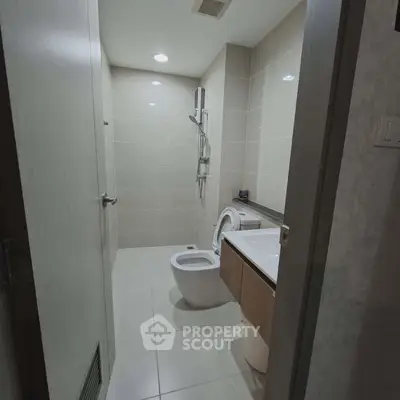 Modern bathroom with sleek fixtures and minimalist design, featuring a spacious shower and contemporary vanity.