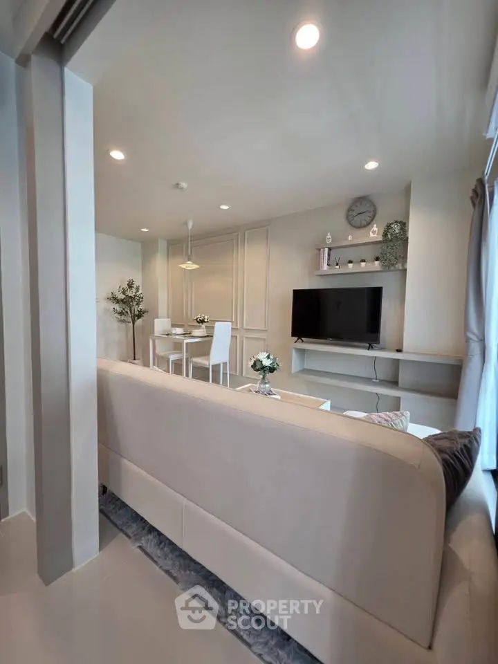 Modern living room with sleek design, featuring a cozy sofa, dining area, and wall-mounted TV for stylish living.