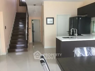 Modern kitchen with sleek design and staircase in open-plan layout
