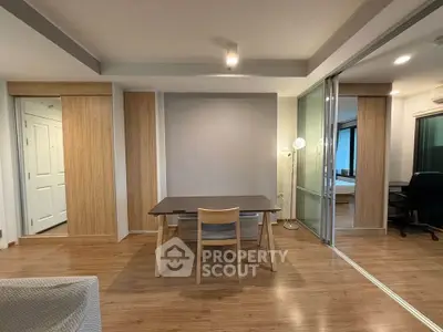 Modern apartment interior with wooden flooring and sliding glass doors, featuring a cozy dining area.
