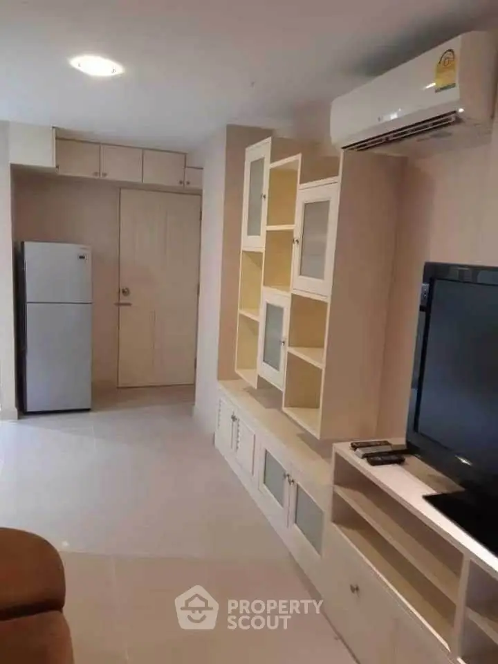 Modern living room with built-in storage and air conditioning, featuring a sleek TV setup.