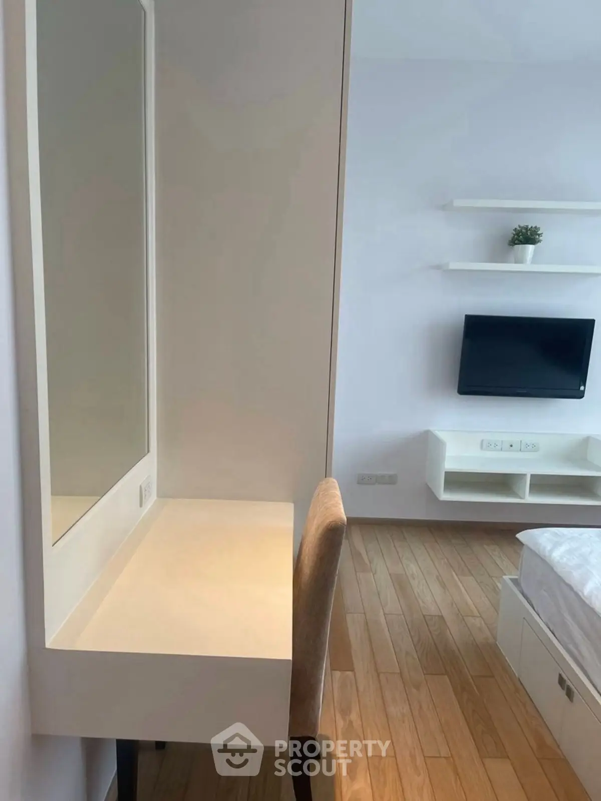 Modern bedroom with sleek furniture and wall-mounted TV, featuring a minimalist design.