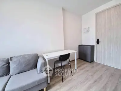 Modern minimalist living room with gray sofa and sleek white desk in a cozy apartment.