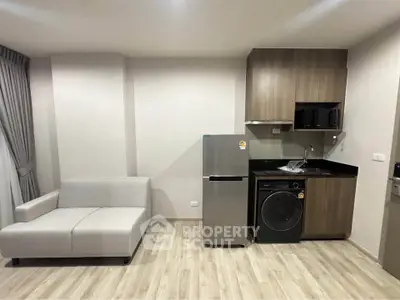 Modern apartment interior with compact kitchen and cozy living area featuring sleek appliances and stylish design.
