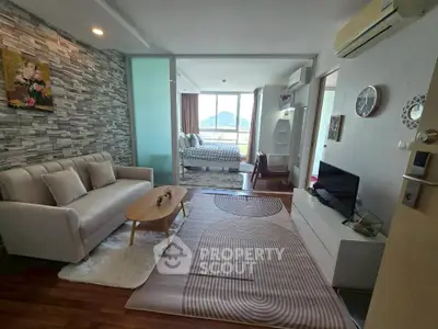 Modern living room with stylish decor and view into a cozy bedroom, featuring a scenic window view.