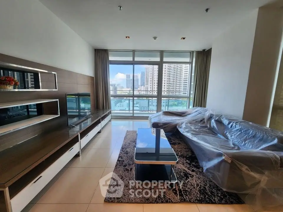 Spacious living room with modern furniture and stunning city view from large windows.