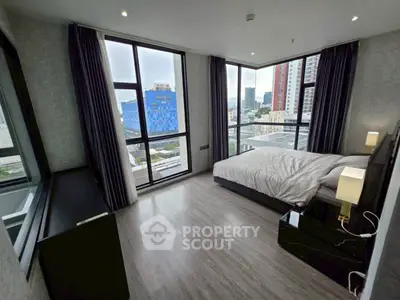 Modern bedroom with large windows and city view in high-rise apartment