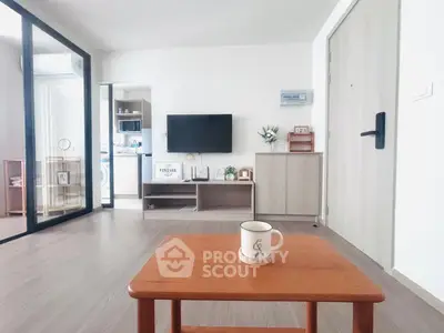 Modern living room with wooden flooring, TV, and stylish decor in a cozy apartment.