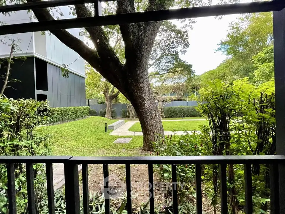 Serene garden view from modern apartment balcony with lush greenery and mature trees