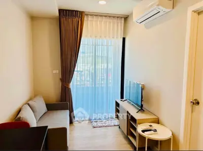 Modern living room with natural light, cozy sofa, and sleek TV setup in a stylish apartment.