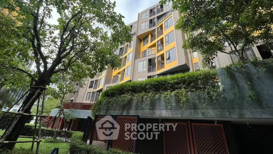 Modern apartment building with lush greenery and vibrant yellow accents