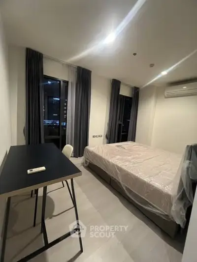 Modern bedroom with sleek design and city view, featuring a desk and air conditioning.