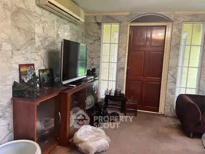 Cozy living room with marble walls and wooden furniture, featuring a TV and decorative items.
