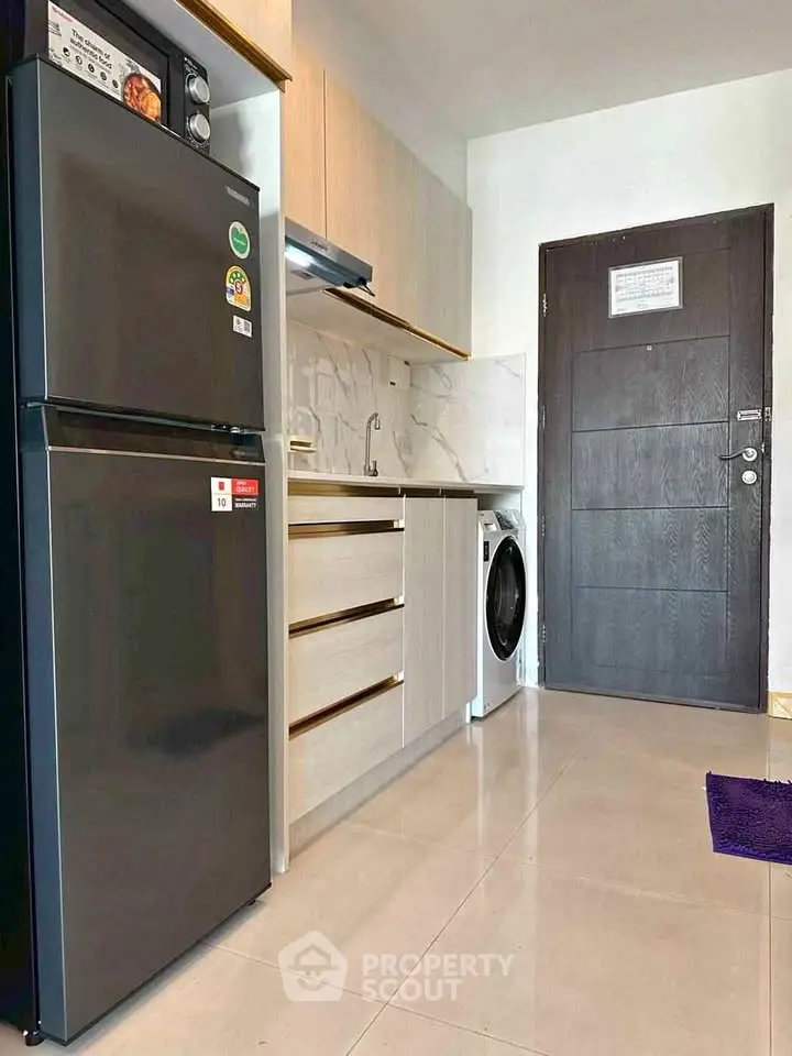 Modern kitchen with sleek appliances and washing machine in compact layout.